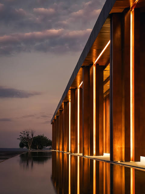 Illuminated colonnade reflected in the venue's water feature at sunset